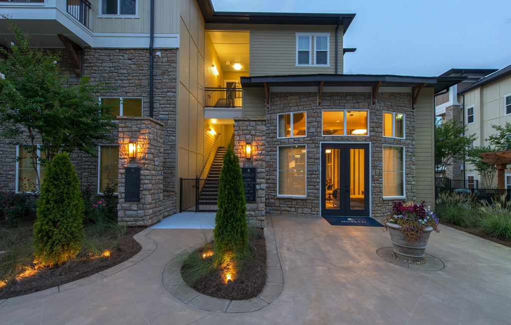 A modern house with a stone facade and a lit up entrance.